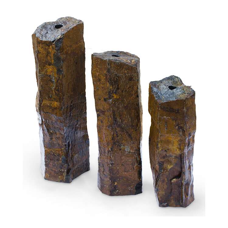 Three rust-skinned basalt columns with drilled tops, ready to plumb as a garden fountain