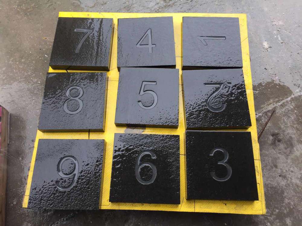 Polished black basalt tiles engraved with numbers 1 to 9, laid out for inspection