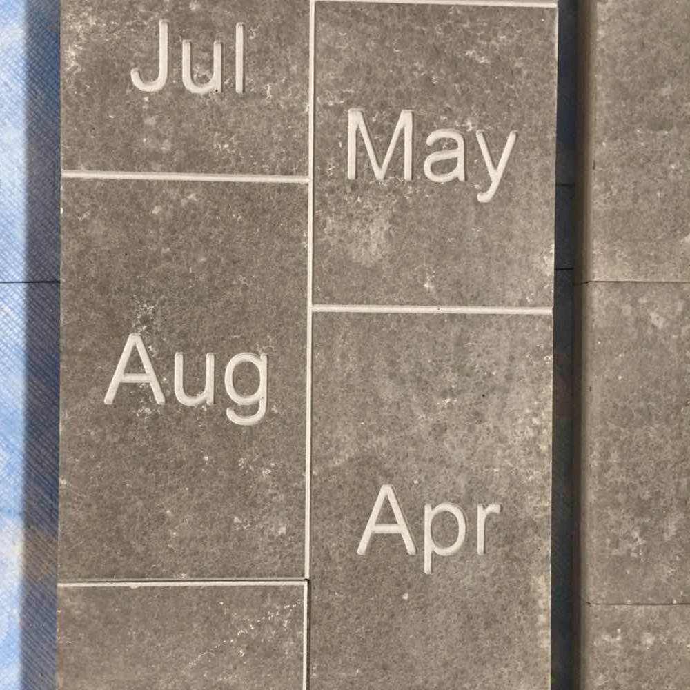 Flamed Mongolia Black basalt pavers engraved with month names, laid as a calendar walkway
