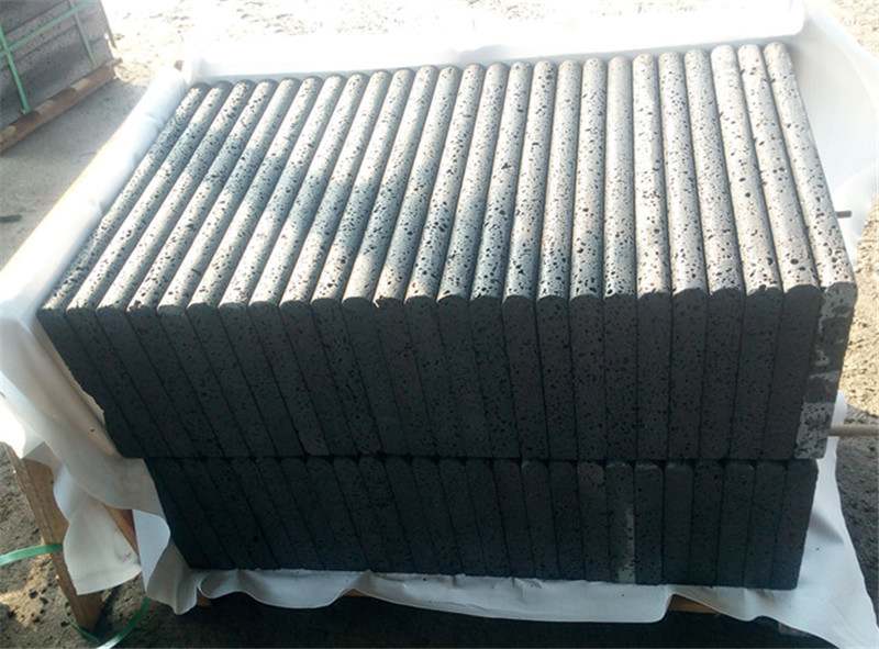 Black lava stone copings packed side by side in a crate