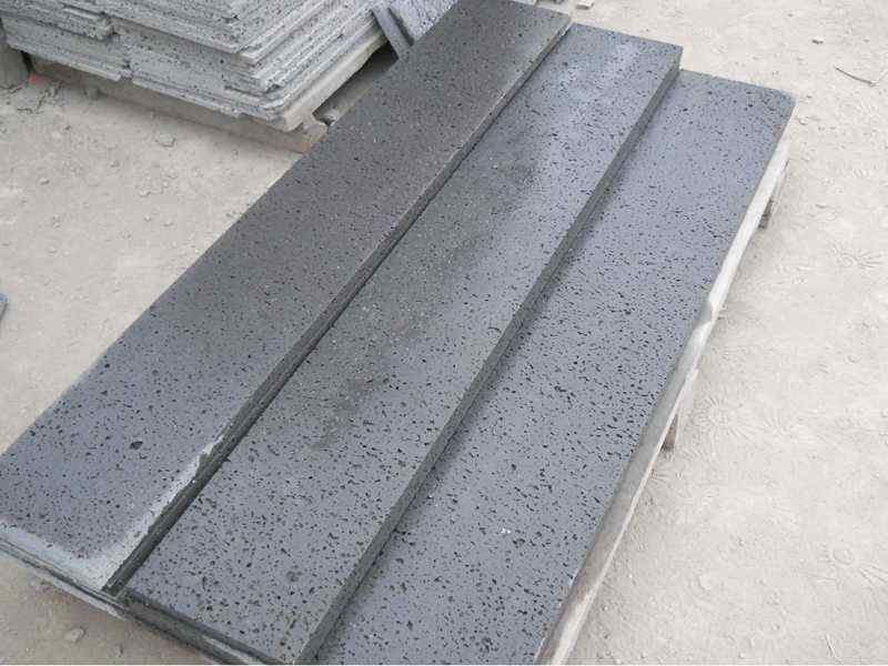 Long black lava stone pool copings stacked on the floor