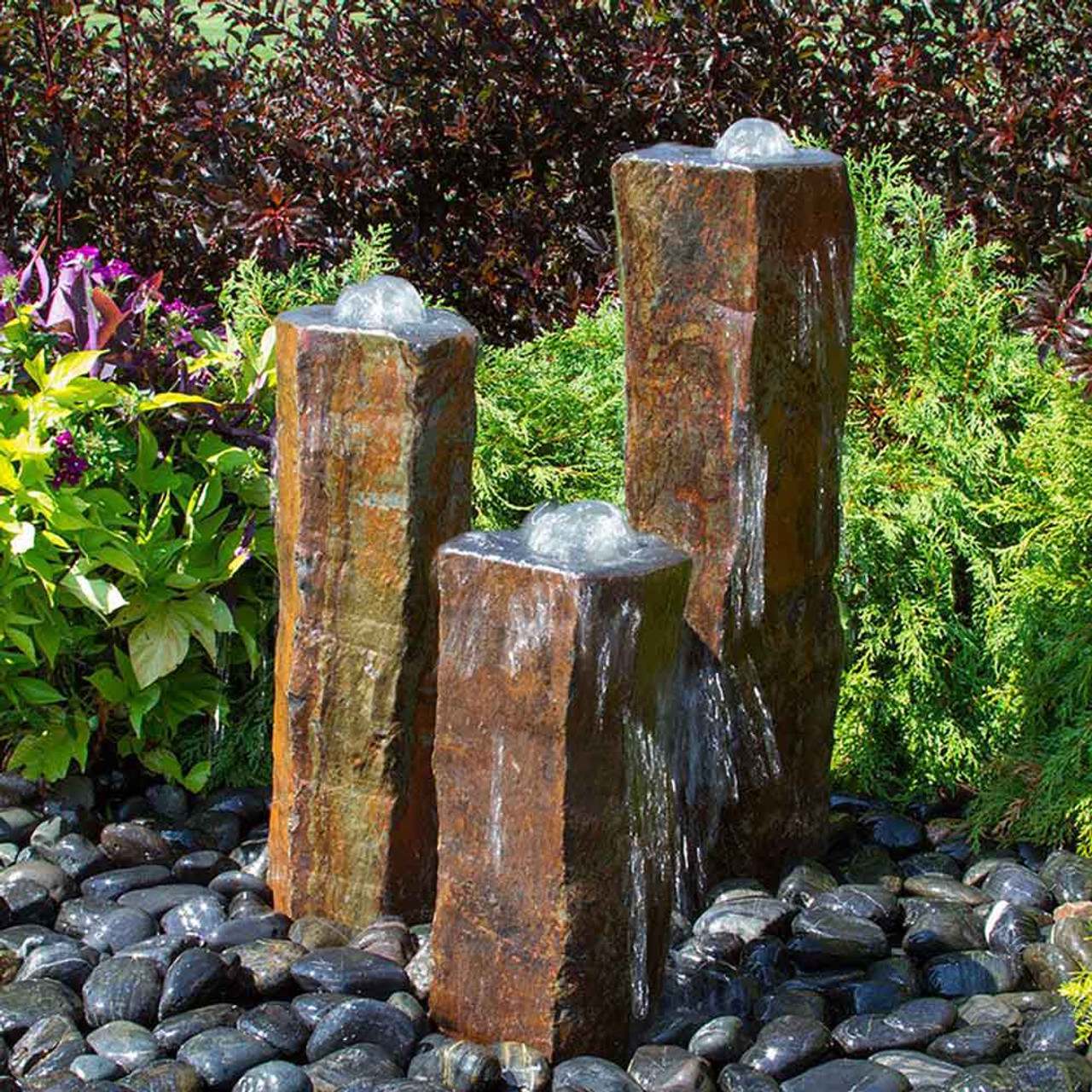 Three bubbling basalt column fountains set in black beach pebbles