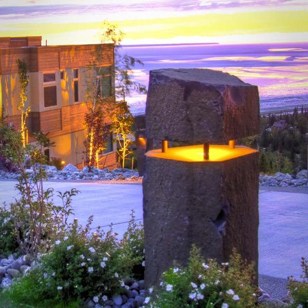 Basalt column lantern lit at dusk on a hillside terrace