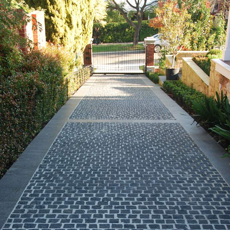 Black basalt cobblestone driveway leading to an entrance gate