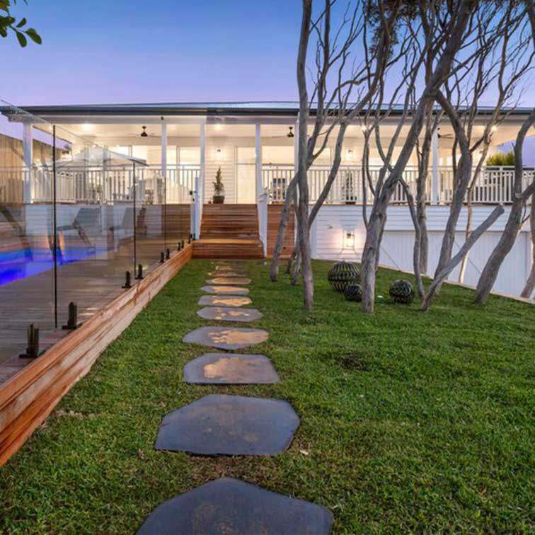 Basalt stepping stones leading across a lawn to a pool deck at dusk