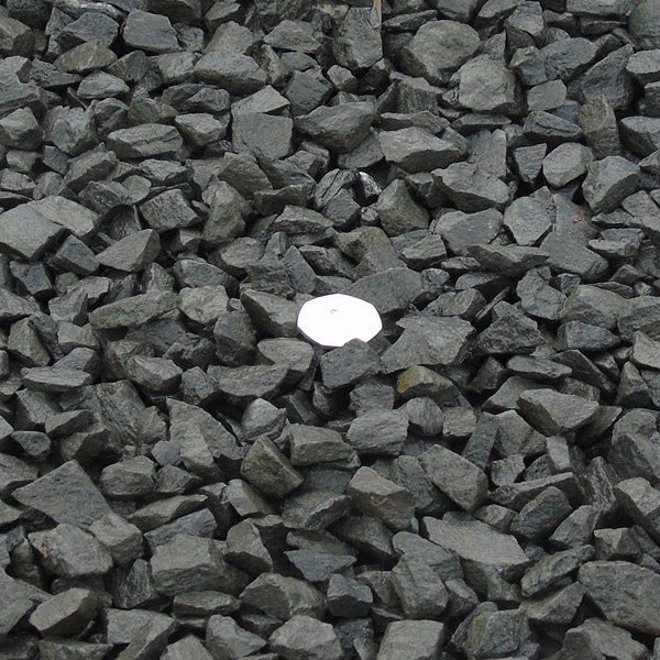 Black basalt gravel for pathways with a coin for scale